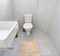 Bathroom in a family house with a sink, toilet, and beige rug.