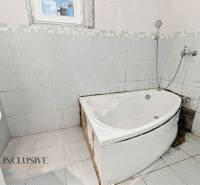 A bathroom with a corner bathtub and white tiles in a family house.