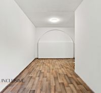 A room in a family house with a wooden decor floor and an arched passageway.