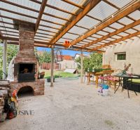 Garden terrace with a brick fireplace in a family house in Komárno, under a pergola.