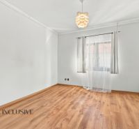 White room with a large window and a wood-patterned floor in a family house.