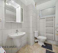 A bathroom in a studio apartment with a sink, bathtub, and ladder radiator.