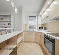 A kitchen in a studio apartment with light-colored cabinets and built-in appliances.