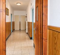 A hallway of a family house with wooden paneling, floor with decorative tiles.