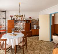 Dining room in a family house with wooden furniture, carpet, chandelier, and decorations.