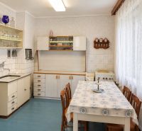 A kitchen in a family house with older furniture, a blue floor, and a white tablecloth.
