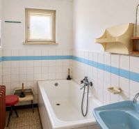 A bathroom of a family house with white tiles and a blue sink.
