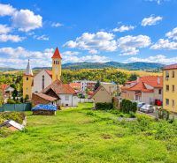 A church surrounded by houses and green landscape in the village of Banka on Topoľčianska Street.