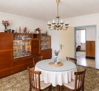 Dining room in a family house with a chandelier, round table, and a display cabinet with glasses.