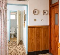 A hallway in a family house with carpet, wood decor, and doors leading to the toilet.