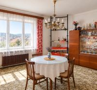 A dining room in a family house with floral curtains and a glass cabinet.