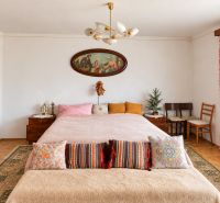 A bedroom in a family house with a stylized interior, a painting, and decorative pillows.