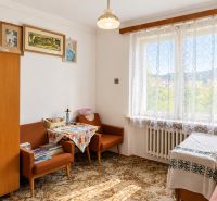 A room in a family house with vintage furniture, decorative paintings, and lace curtains.