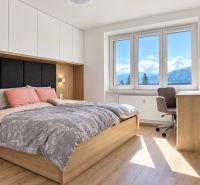 A bright bedroom with a bed, a desk, and a wooden floor decor in a 3-room apartment.