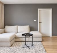 A living room in a three-room apartment with a wooden decor floor and a light-colored sofa.