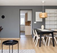 Dining area in a three-room apartment, with a wooden decor floor and gray walls.