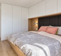 Bedroom in a 3-room apartment with a bed, built-in wardrobes, and a floor with a wooden decor.