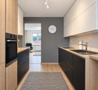 A kitchen in a 3-room apartment with storage cabinets and a wooden decor floor.