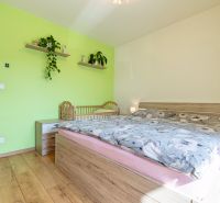 Bedroom in a three-room apartment decorated with a green wall, floor with wood decor.