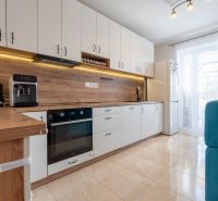 A kitchen in a 3-room apartment with white cabinets and a wood-patterned floor.