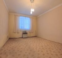 An empty room in a family house with a carpet, a heater, and curtains on the window.