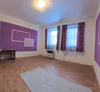 A room in a family house with purple walls and a wooden-patterned floor.