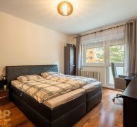 A bedroom in a three-room apartment with a wood-patterned floor and a bunk bed.
