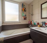 A bathroom with a bathtub and a sink in a 3-room apartment with a lot of toiletries.