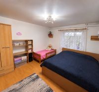 A bedroom in a one-room apartment with shelves, two beds, wooden decor, and a wardrobe.