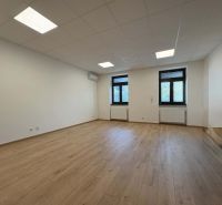 A spacious office with white walls and a wooden decor floor.