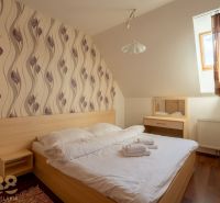 A bedroom in a two-room apartment with a bed, wallpaper, and a wooden decor floor.