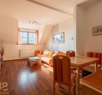 Living room of a two-room apartment with a wooden decor floor and orange furniture.