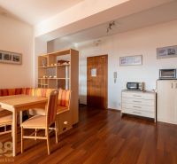 Living room in a two-room apartment with a dining table and a wooden decor floor.