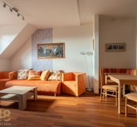 Living room in a two-room apartment with orange furniture and a wooden decor floor.