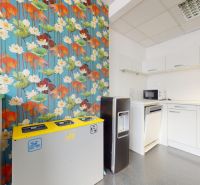 An office with colorful wallpaper, a sink, a microwave, trash bins, and a water dispenser.