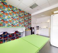 Offices with colorful wallpaper, green desks, and a kitchenette.
