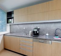 Office kitchen area with wooden cabinets and a large window with blinds.