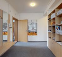 The interior of an office with carpet flooring, open shelves, and hooks for hanging clothes.
