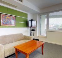 Comfortable seating in the office with a picture and a television on the wall.