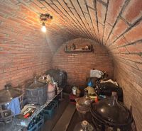 A brick-walled cellar with stored demijohns and bottles in a family house.