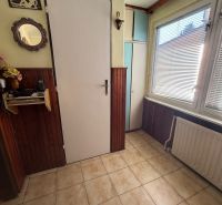 Tiled entrance hall in a family house with wooden wall paneling and a mirror.