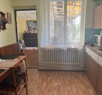 A kitchen in a family house with a wooden decor floor, curtains, and furniture.