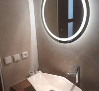 A bathroom with a mirror with LED lighting and a modern sink in a studio apartment.