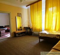A room in a family house with yellow curtains and simple furniture.