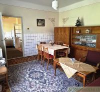 Living room with retro decor, patterned carpet, and wooden furniture in a family house.