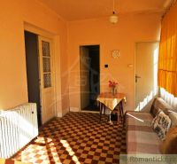 Interior of a family house with a sofa, table, radiator, and checkered floor.