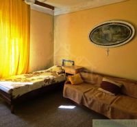 A room in a family house with a bed, a sofa, and yellow curtains.