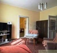 A living room of a family house with comfortable armchairs and a TV on a stand.