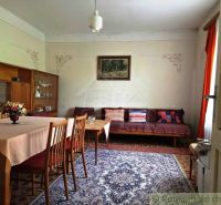 The dining room of a family house with a carpet, wooden furniture, and decorative curtains.