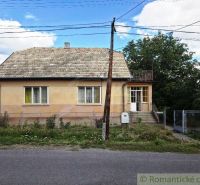 A family house in Sečianky with a garden, fence, and veranda on a sunny street.